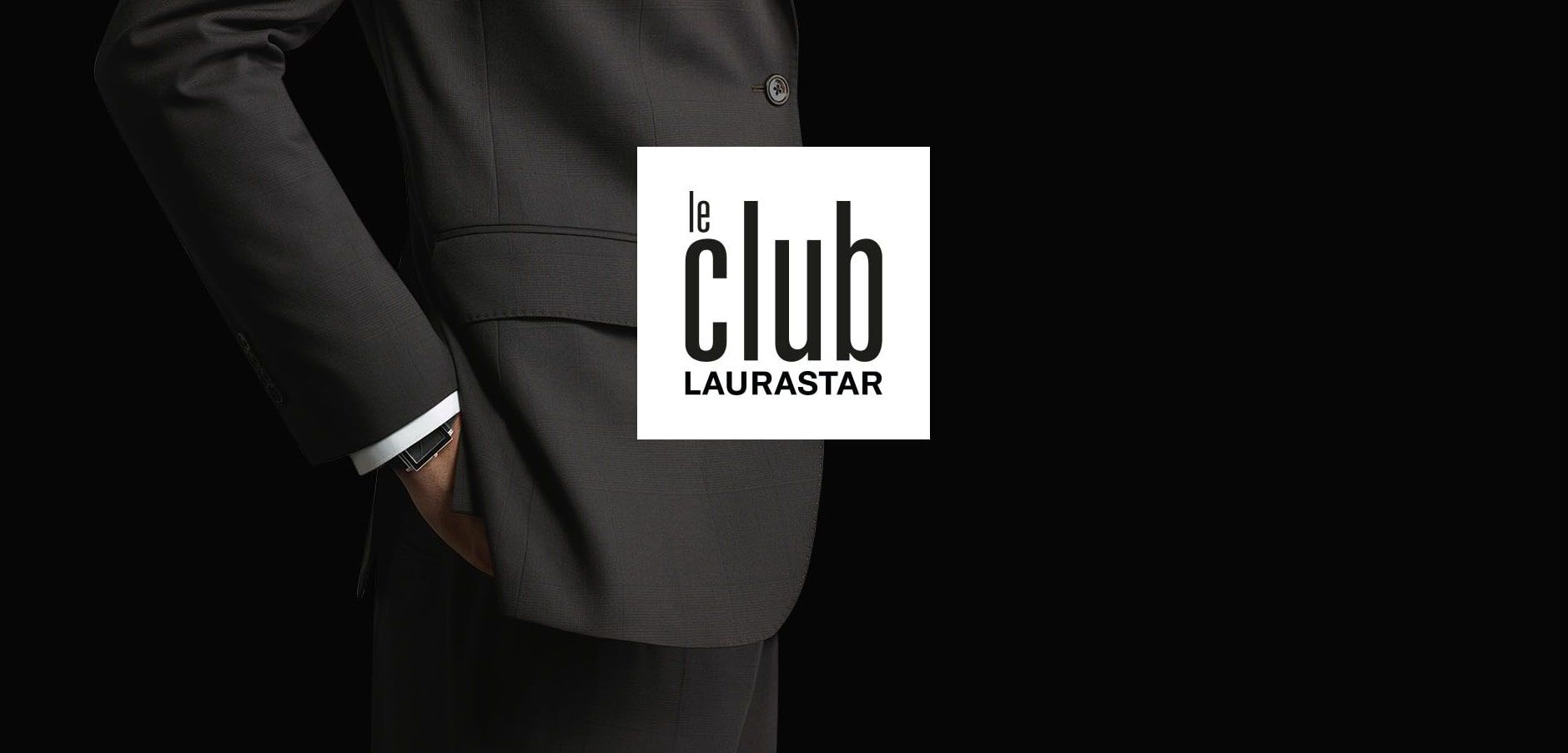 A person in a dark suit with one hand in their pocket is shown on a black background, with the 