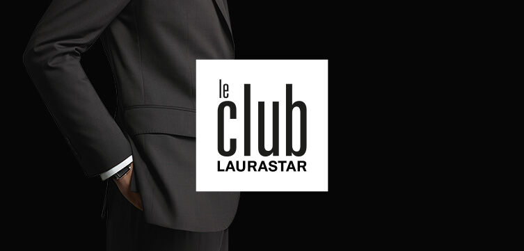 A person in a dark suit with one hand in their pocket is shown on a black background, with the 